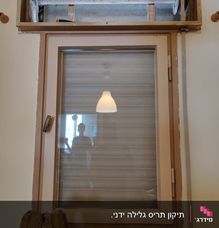 חלון עם תריסים סגורים ומסגרת עץ חשופה